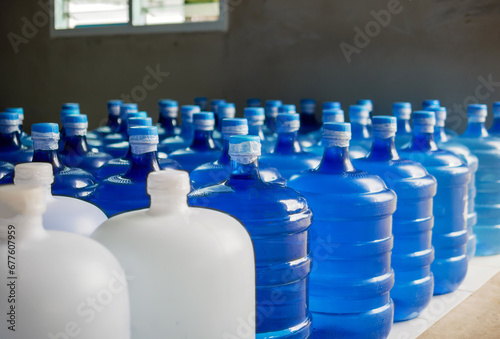 plastic big bottles or white and blue gallons of purified drinking water inside the production line. Water drink factory