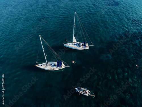 Sailing yachts anchored in blue sea, top view. Sailing yacht on dark background, aerial view.