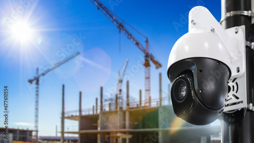 CCTV camera at construction site. Dome camera near house under construction. Ensuring safety of erection of building. CCTV equipment. Camera surveillance near block under construction photo