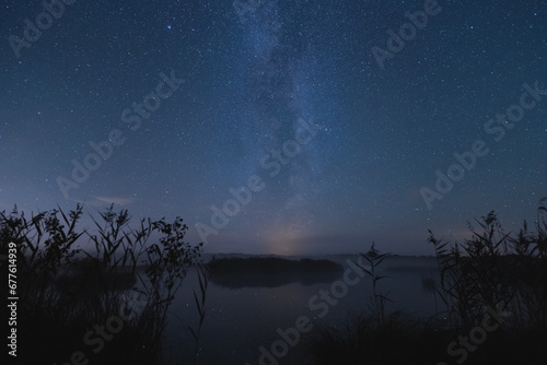 Night scene, nature of Estonia. Milky Way on a lake in the forest.