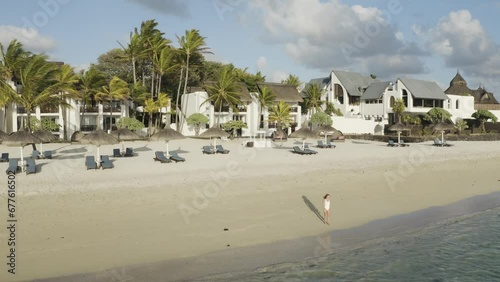 Aerial view of a woman on the beach along the shore with umbrellas at sunset, Ilot Lievres, Trou d'Eau Douce, Flacq district, Mauritius. photo