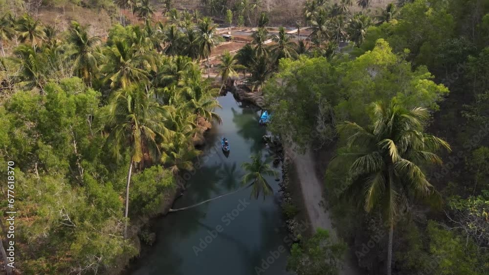 aerial view of blue boats running on the Cokel river, Pacitan, Indonesia. The river has coconut trees on its banks. aerial view of blue boats running on the Cokel river, Pacitan, Indonesia. The river has coconut trees on its banks.