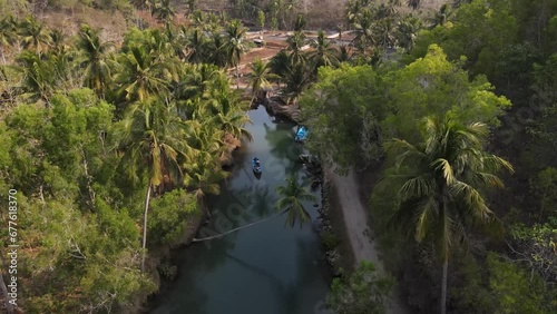 aerial view of blue boats running on the Cokel river, Pacitan, Indonesia. The river has coconut trees on its banks. photo