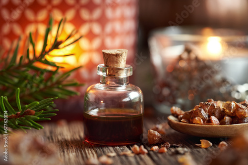 A bottle of myrrh essential oil with spruce branches and candle at Christmas photo