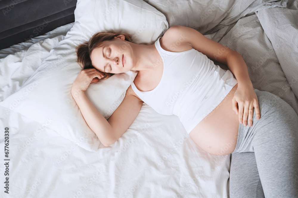 Pregnant woman relaxing or sleeping in bed. Pregnancy concept. - obrazy, fototapety, plakaty 