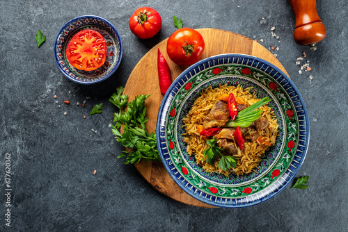 uzbek hot dish of boiled rice, chicken meat, vegetables and spices pilaf in plate with oriental ornament, banner, menu, recipe place for text, top view