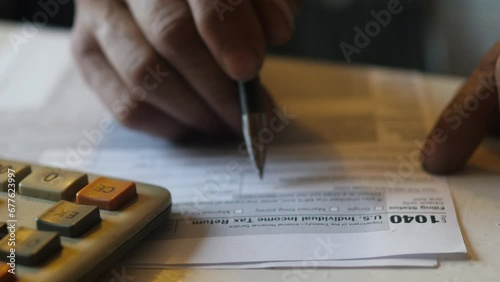 US Individual Income Tax Return Forms 1040. A retiree fills out an income tax return form. Budget concept.