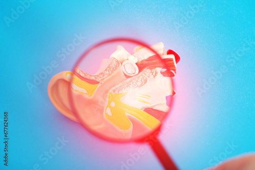 Medical mockup of an inflamed ear on a blue background under a magnifying glass. Concept of ear diseases, otitis media and eustachitis. Otolaryngology, close-up photo