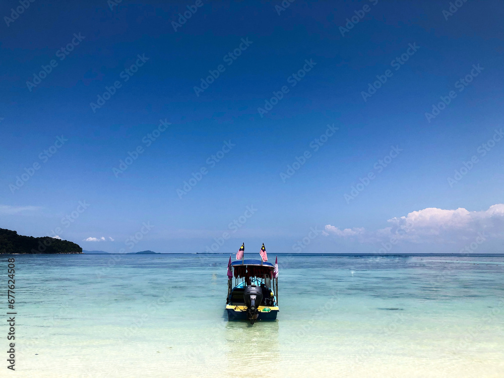 a boat anchored on the white beach shores of Perhentian Island, Terengganu looking towards the sea.