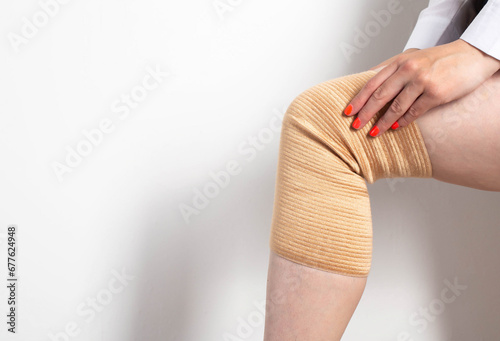 Orthopedic medical kneecap on the leg of a girl. Micromassage and warming effect in inflammatory diseases of the knee. Copy space for text