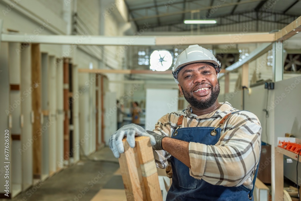 Carpenter man Portrait of Young black skin looking smile laugh to camera in workshop. Happy professional Carpenter holds wooden planks for build furniture in carpentry workshop. one carpenter worker