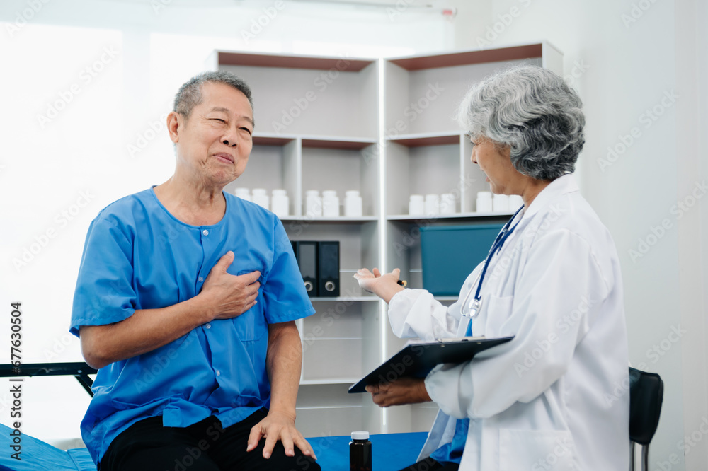 Asian doctor in white suit take notes while discussing and Asian elderly, man patient who lying on bed with receiving saline solution Asian doctor in white suit take notes while discussing and Asian elderly, man patient who lying on bed with receiving saline solution