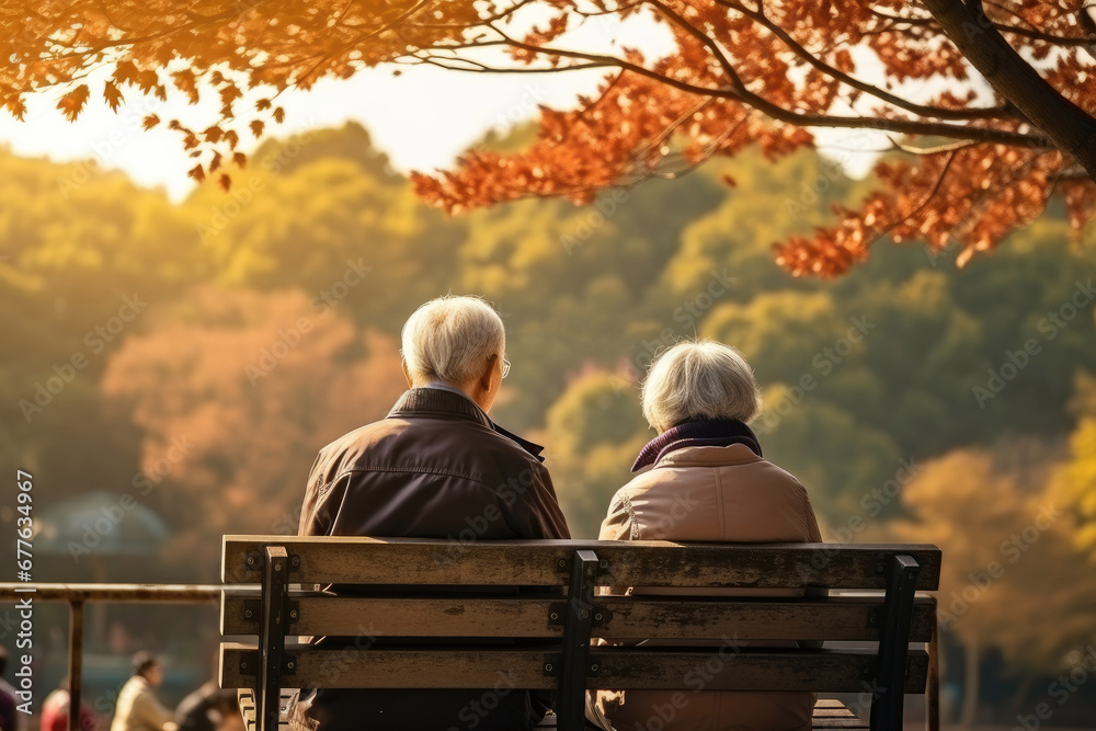 Happy Asian elderly couple sitting on park bench against autumn landscape background Happy Asian elderly couple sitting on park bench against autumn landscape background