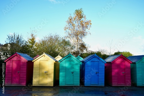 Colourful Beach Huts in a row under a blue sky. 