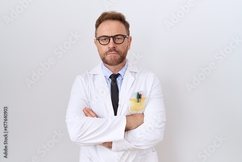 Middle age doctor man with beard wearing white coat skeptic and nervous, disapproving expression on face with crossed arms. negative person. photo