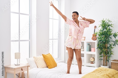 African american woman smiling confident dancing on bed at bedroom
