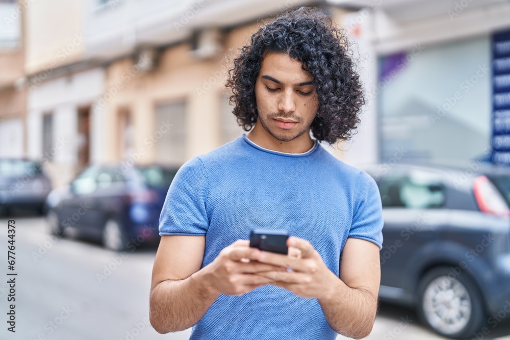 Young latin man using smartphone with serious expression at street Young latin man using smartphone with serious expression at street
