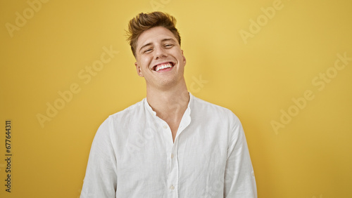 Laughing, confident young caucasian man in casual fashion, standing isolated against a yellow background, radiating positive vibes and joy © Krakenimages.com