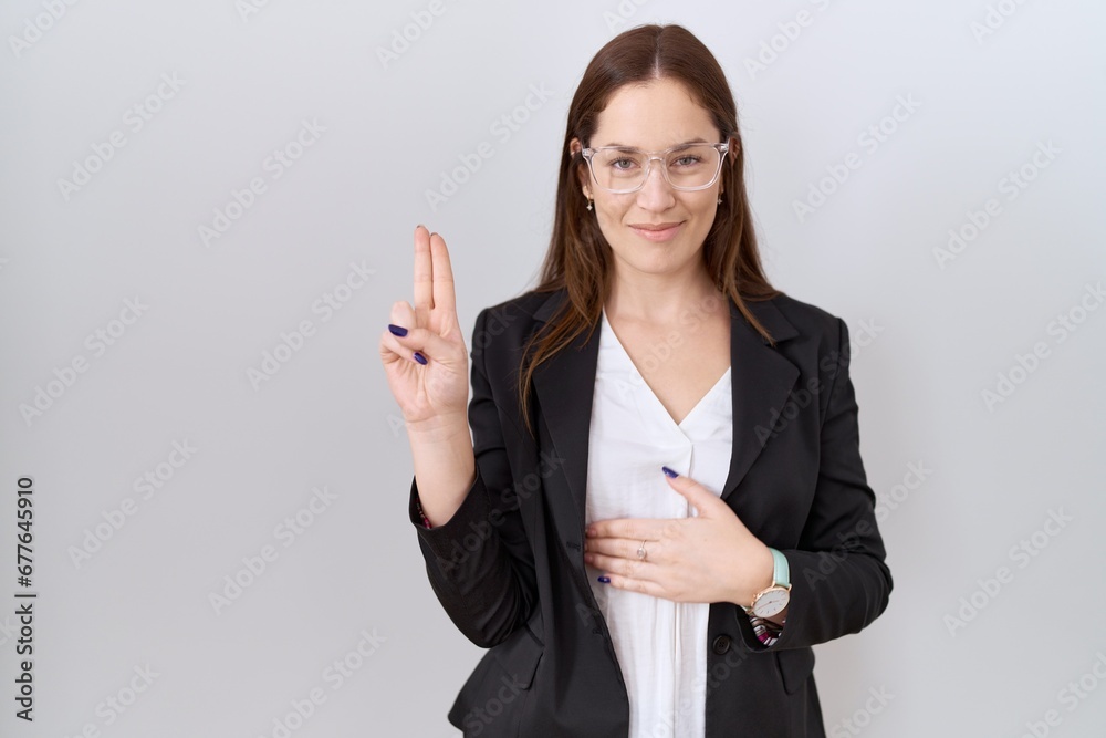 Beautiful brunette woman wearing business jacket and glasses smiling swearing with hand on chest and fingers up, making a loyalty promise oath Beautiful brunette woman wearing business jacket and glasses smiling swearing with hand on chest and fingers up, making a loyalty promise oath
