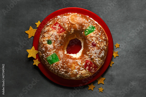 Canvas Print Top view of Roscon de reyes on a red plate with golden stars