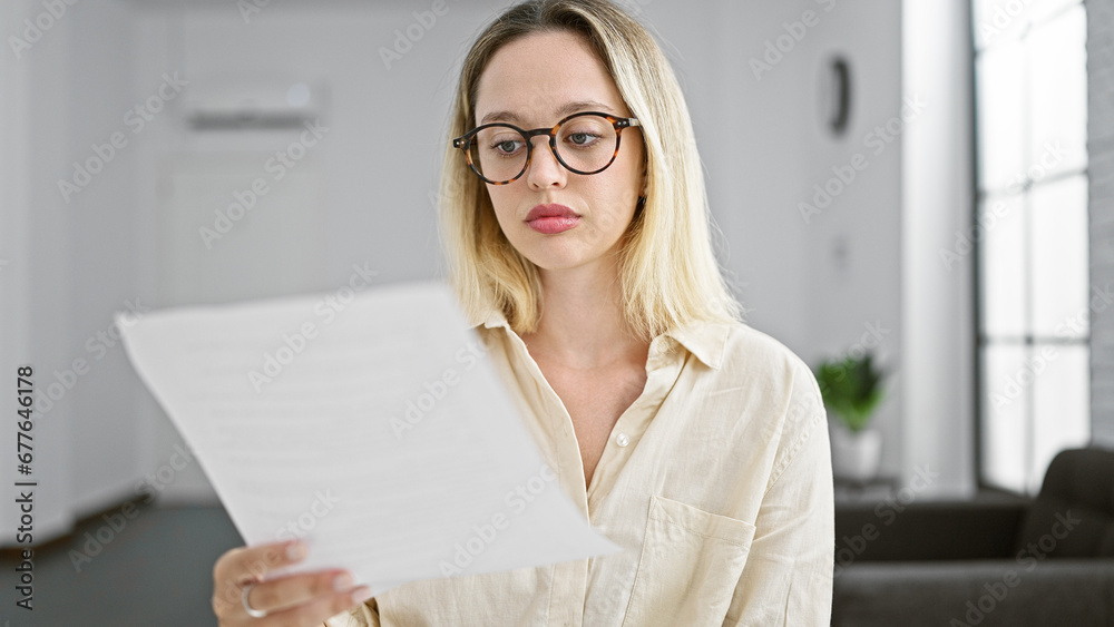 Young blonde woman business worker reading document looking upset at the office Young blonde woman business worker reading document looking upset at the office