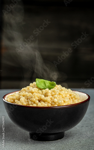 cooked ptitim pasta in a bowl with hot steam, vertical image. copy space for text