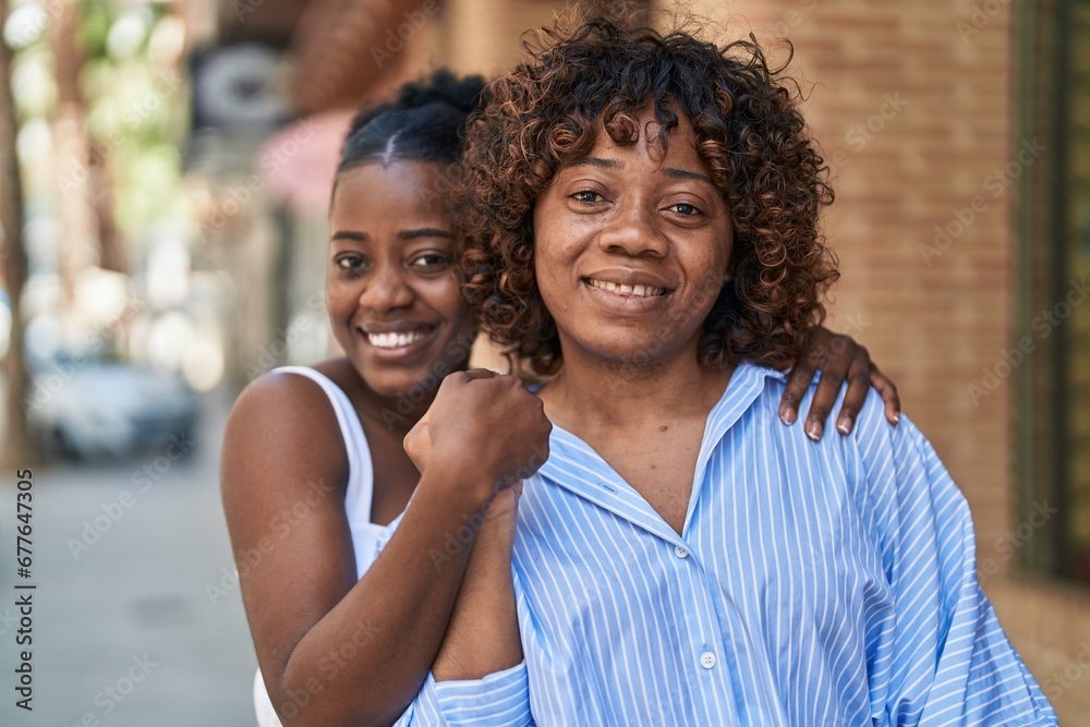 Fototapeta premium African american women mother and daughter hugging each other at street