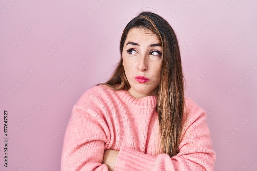 Young hispanic woman standing over pink background looking to the side with arms crossed convinced and confident Young hispanic woman standing over pink background looking to the side with arms crossed convinced and confident