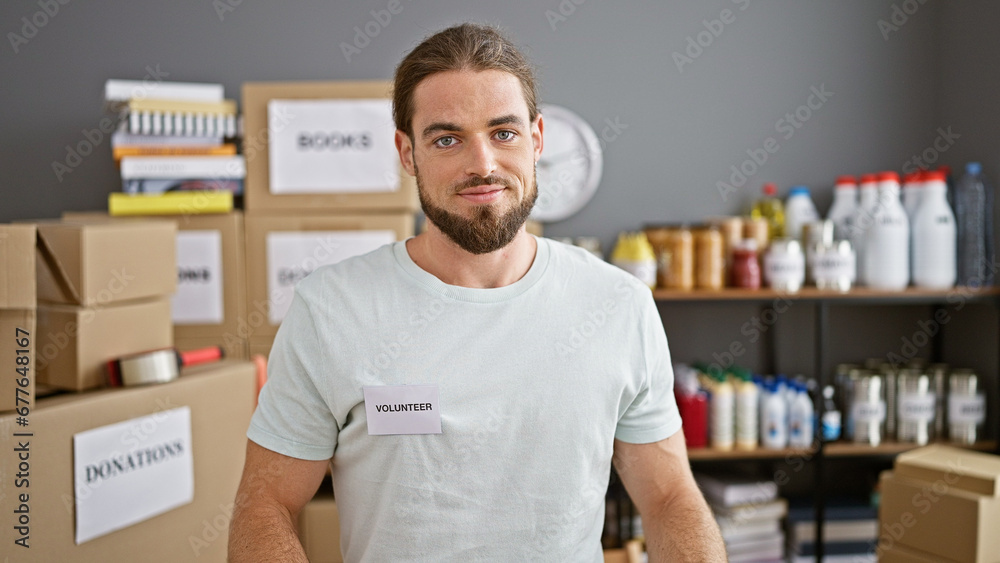 Fototapeta premium Young hispanic man volunteer standing with relaxed face at charity center