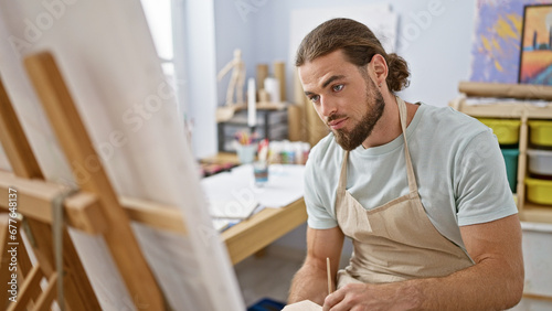 Young hispanic man artist drawing at art studio