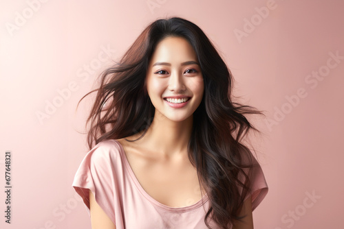 Pretty young Asian woman smiling looking at camera on plain background.