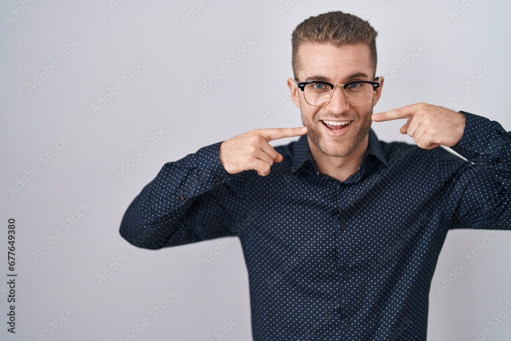 Young caucasian man standing over isolated background smiling cheerful showing and pointing with fingers teeth and mouth. dental health concept. Young caucasian man standing over isolated background smiling cheerful showing and pointing with fingers teeth and mouth. dental health concept.