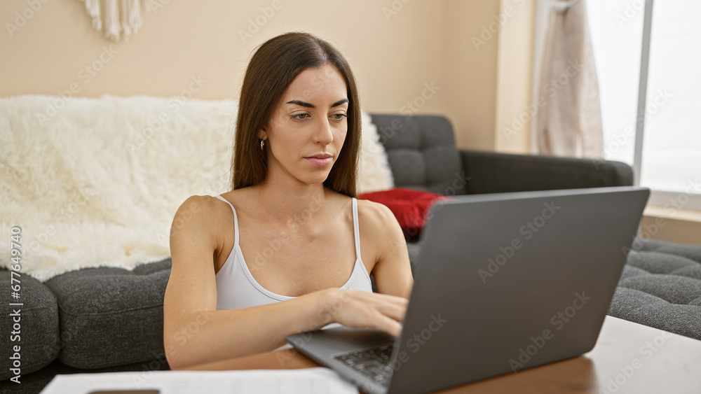 Attractive hispanic woman, bright-eyed and focused, using her laptop while sitting on the floor of her cozy home, fully immersed in the world of technology Attractive hispanic woman, bright-eyed and focused, using her laptop while sitting on the floor of her cozy home, fully immersed in the world of technology