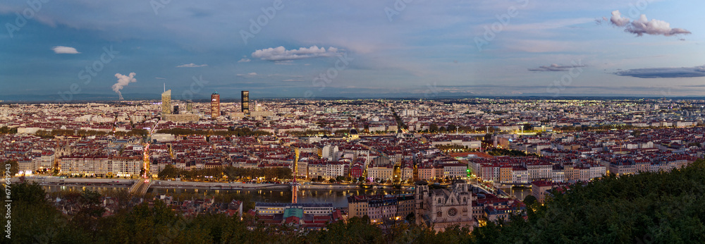 Panorama of Lyon from Fourviere hill in the early evening, showing city lights and distant alps mountains, Lyon, France