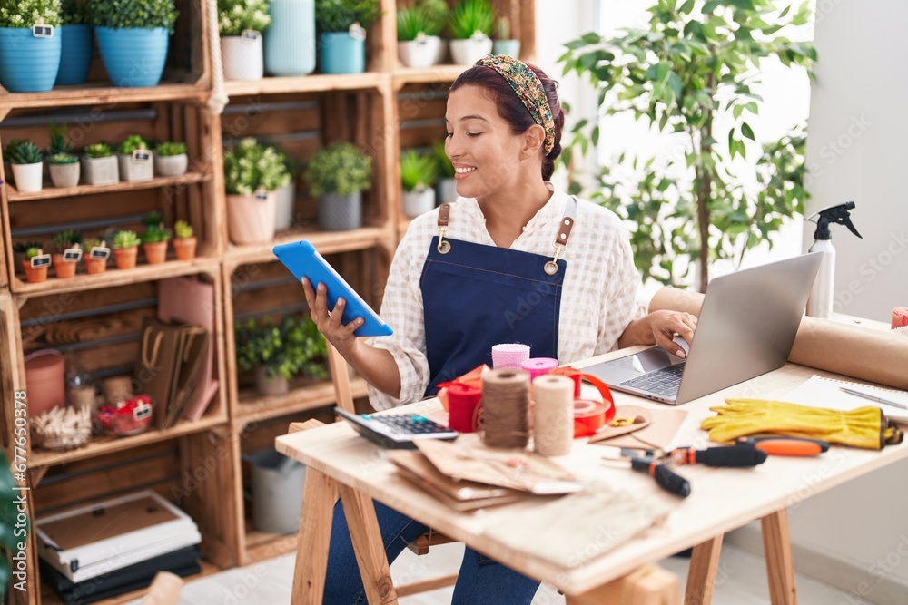 Young beautiful hispanic woman florist smiling confident using touchpad and laptop at florist Young beautiful hispanic woman florist smiling confident using touchpad and laptop at florist