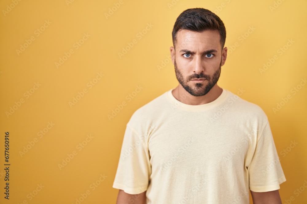 Handsome hispanic man standing over yellow background skeptic and nervous, frowning upset because of problem. negative person. Handsome hispanic man standing over yellow background skeptic and nervous, frowning upset because of problem. negative person.