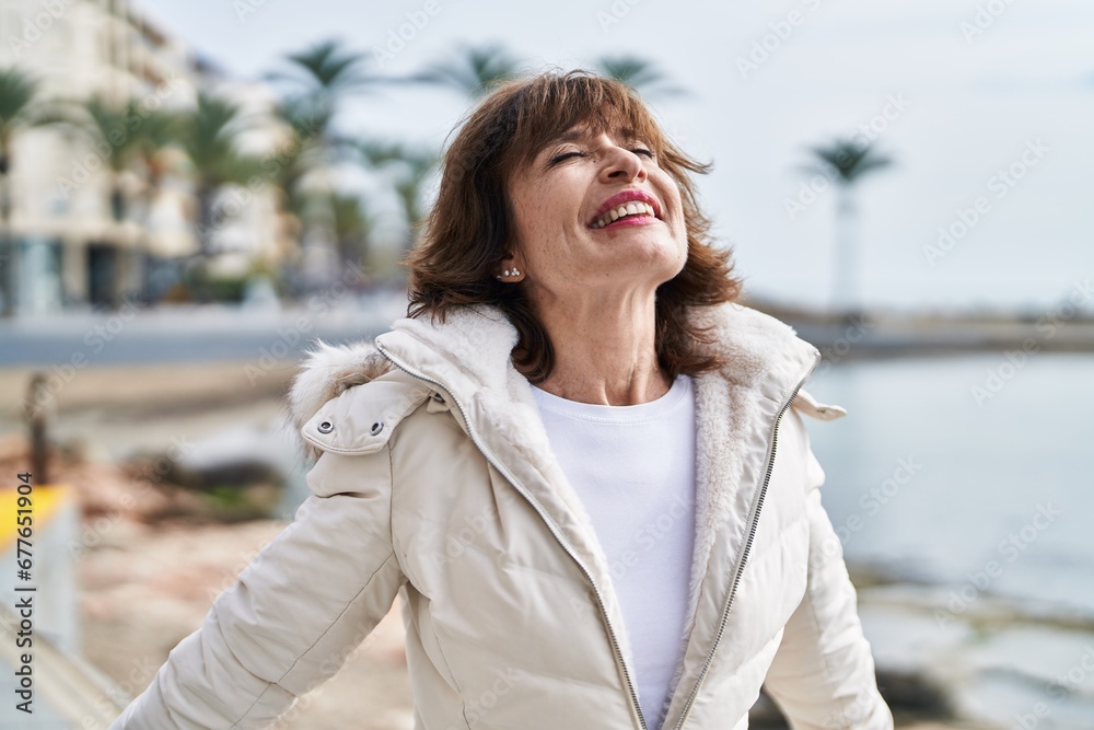Middle age woman breathing with closed eyes at seaside Middle age woman breathing with closed eyes at seaside