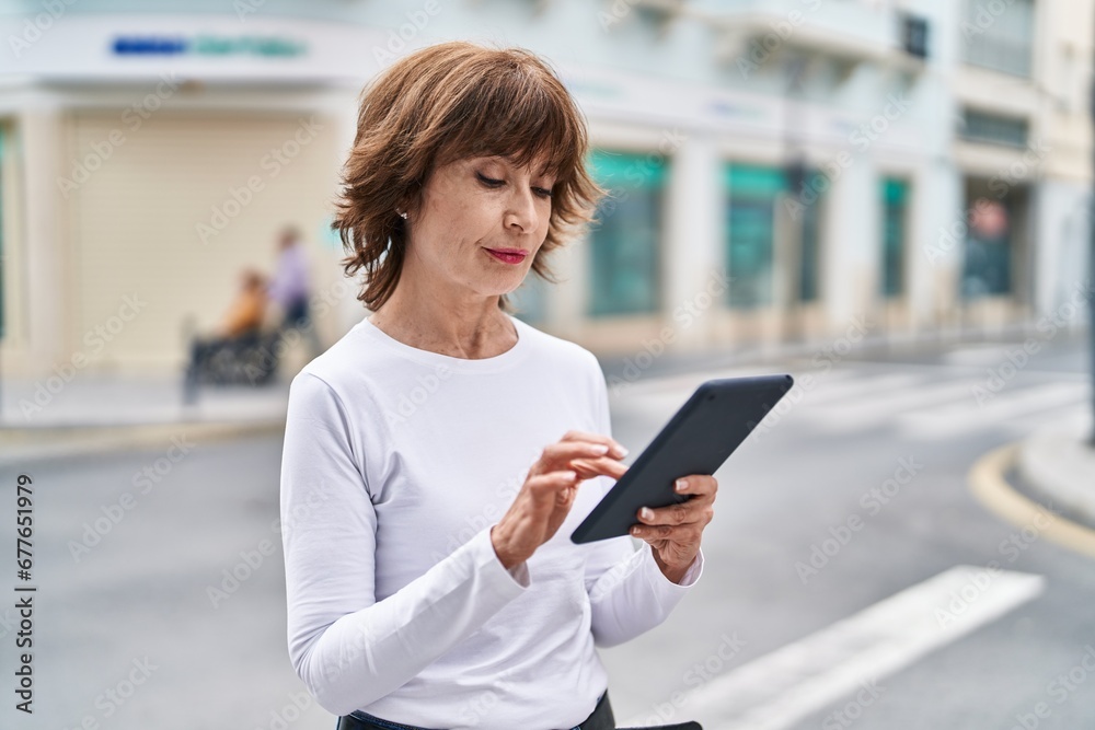 Middle age woman using touchpad with serious expression at street Middle age woman using touchpad with serious expression at street
