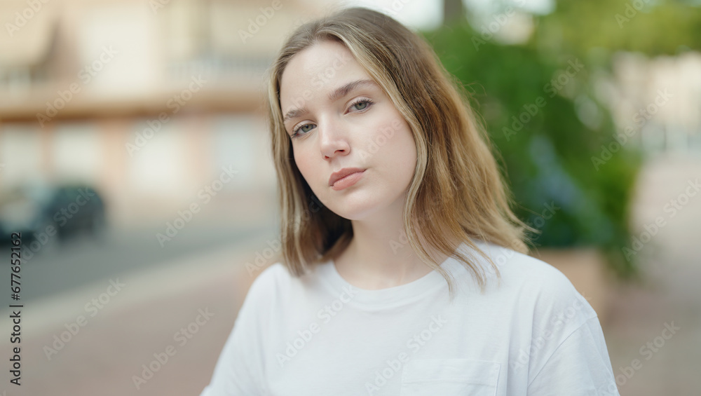 Young caucasian woman standing with serious expression at park