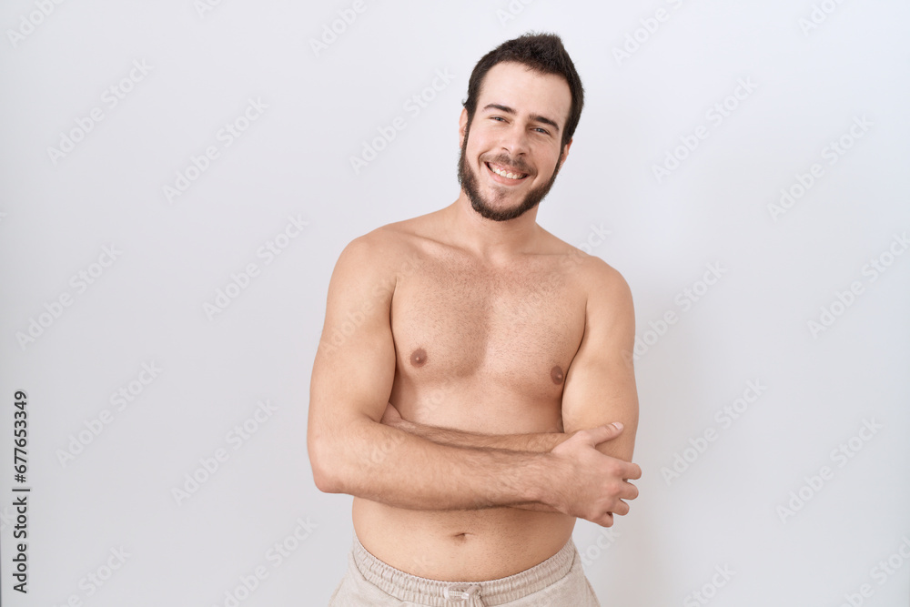 Young hispanic man standing shirtless over white background happy face smiling with crossed arms looking at the camera. positive person.