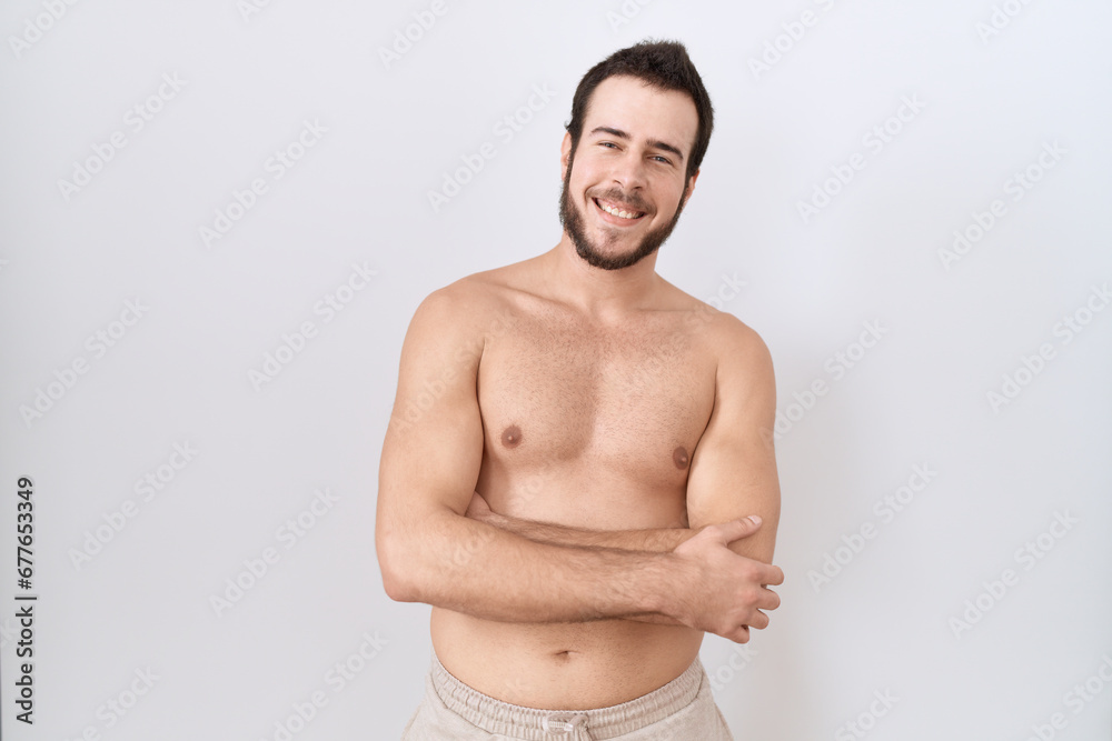 Young hispanic man standing shirtless over white background happy face smiling with crossed arms looking at the camera. positive person. Young hispanic man standing shirtless over white background happy face smiling with crossed arms looking at the camera. positive person.