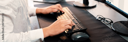 Office worker sitting on workspace desk, focused and engaged, using computer and typing on keyboard to input data ensure accurate data management in the modern workplace. Trailblazing photo