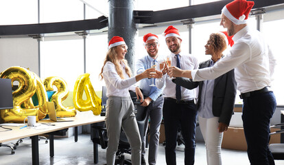 Business people are celebrating holiday in modern office drinking champagne and having fun in coworking. Merry Christmas and Happy New Year 2024