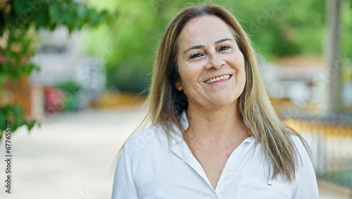 Middle age hispanic woman smiling confident standing at park