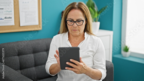 Middle age hispanic woman business worker using touchpad at the office