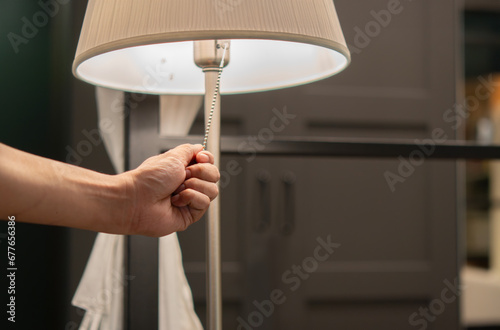 Hand of person is turning on or turning off the bedroom 's head lamp which is beautiful luxury-modern designed.