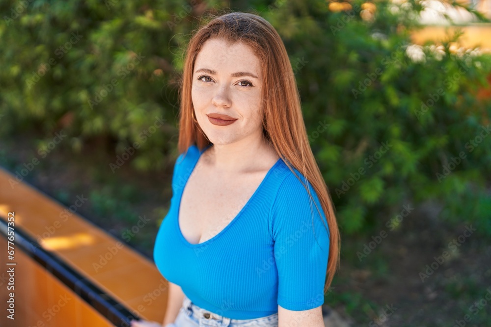Young redhead woman smiling confident sitting on bench at park Young redhead woman smiling confident sitting on bench at park