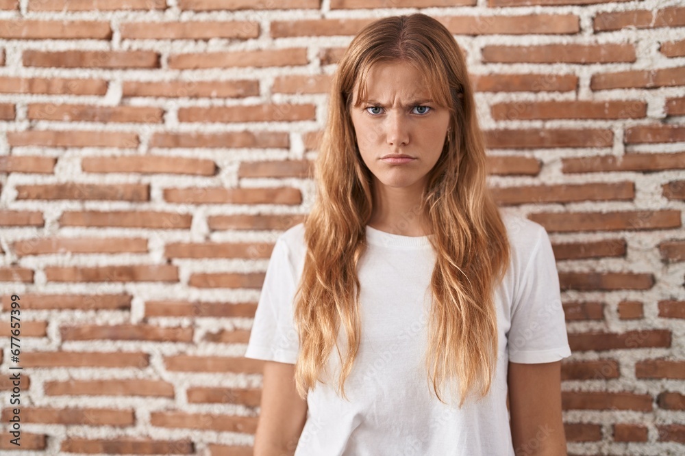 Young caucasian woman standing over bricks wall skeptic and nervous, frowning upset because of problem. negative person. Young caucasian woman standing over bricks wall skeptic and nervous, frowning upset because of problem. negative person.