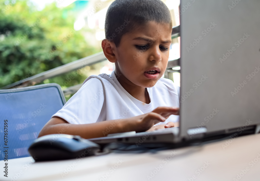 Little boy sitting at table using laptop for online class in Grade 1, Child studying on laptop from home for distance learning online education, School boy children lifestyle concept Little boy sitting at table using laptop for online class in Grade 1, Child studying on laptop from home for distance learning online education, School boy children lifestyle concept
