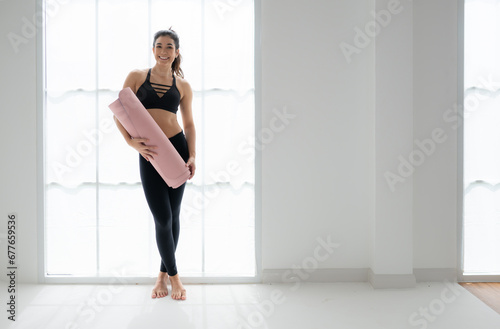 Full length portrait of a young woman holding yoga mat isolated on white background